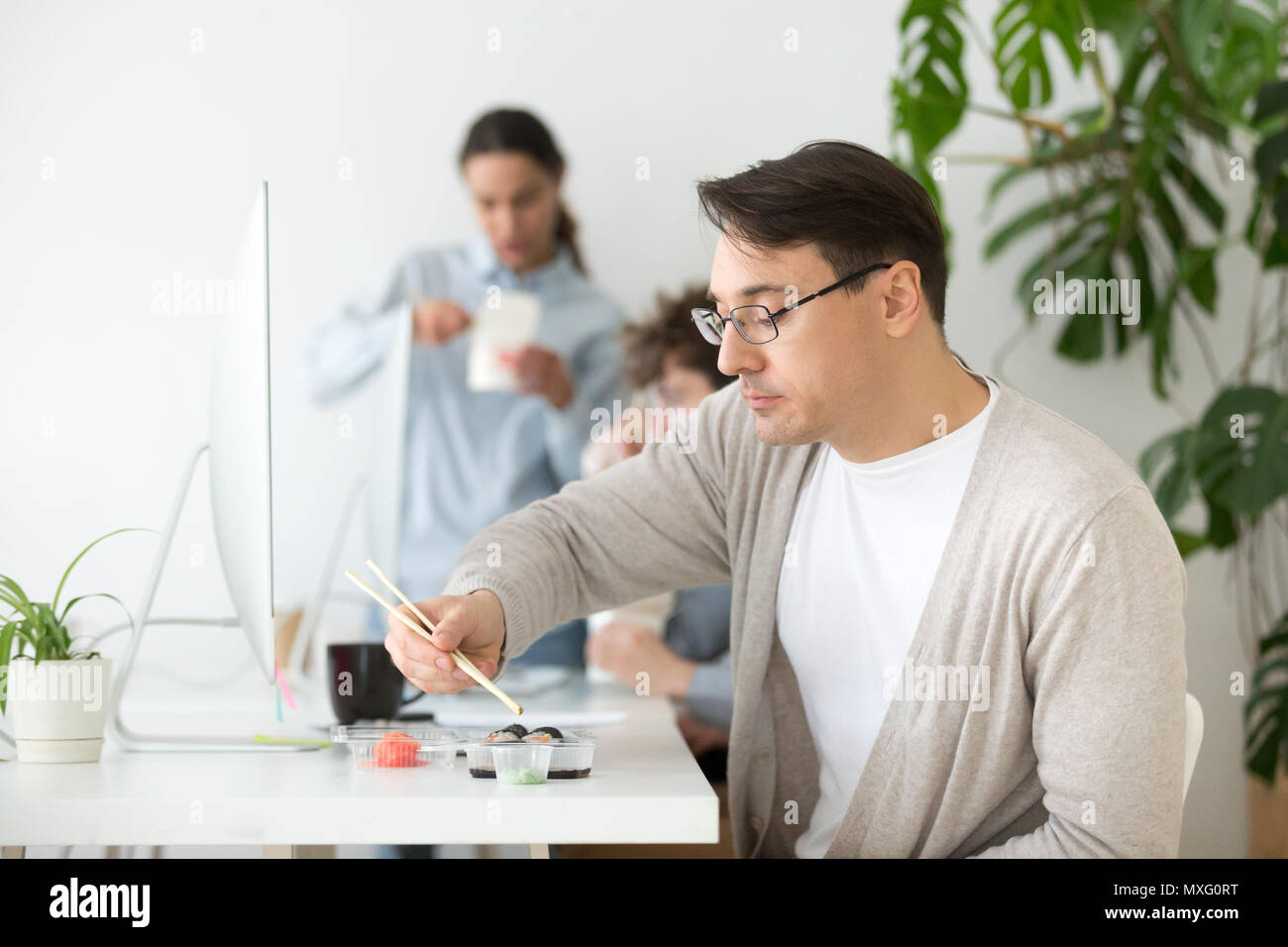 Middle aged worker eating sushi during office work break Stock Photo
