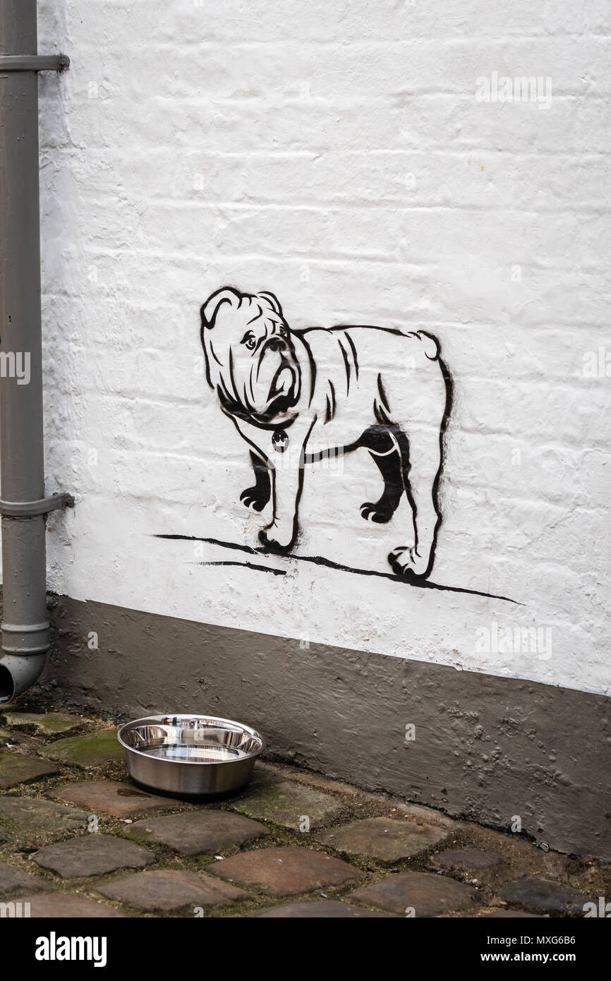 A stencil drawing of a dog on a wall by a bowl of water Stock Photo
