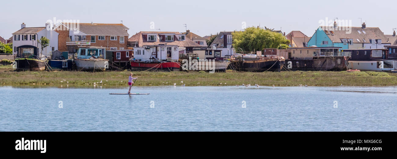 Shoreham-By-Sea; 3rd June 2018; Panorama of Female on a Paddle Board Passing Houseboats on a Riverbank Stock Photo