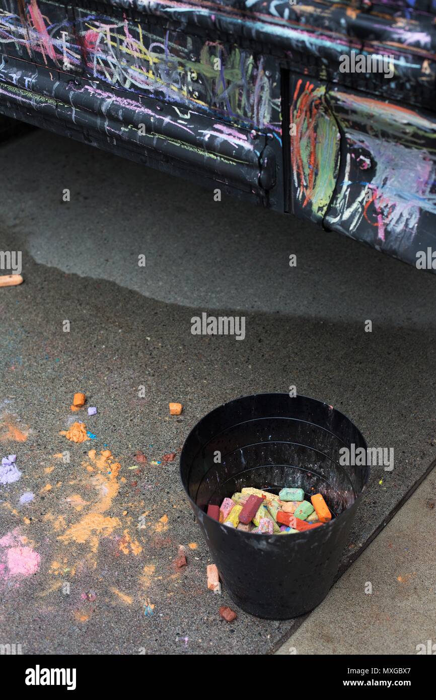 A bucket of colorful chalk next to a black bus at the Minneapolis-St. Paul Mini Maker Faire in St. Paul, Minnesota, USA. Stock Photo
