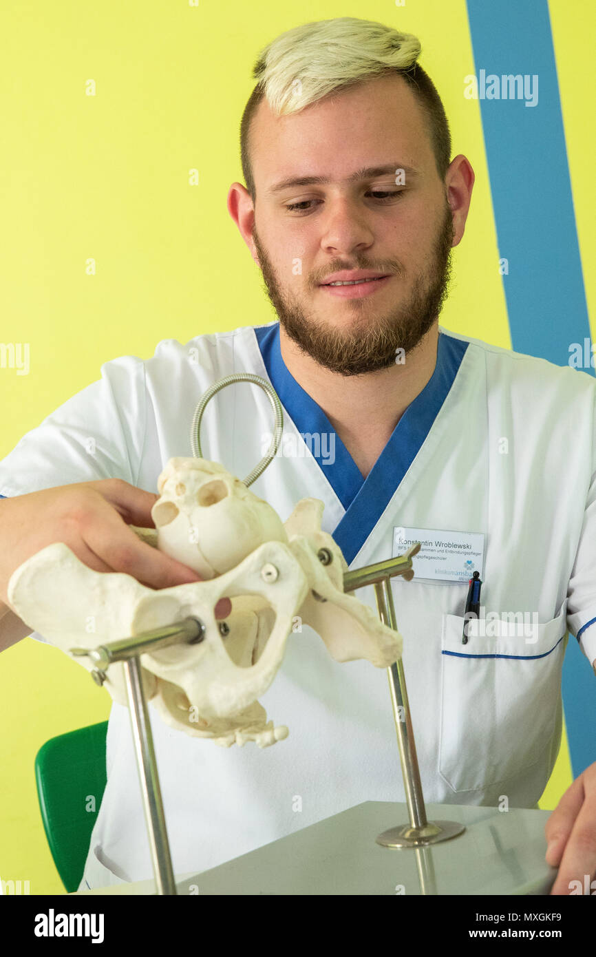 29 May 2018, Germany, Ansbach: Konstantin Wroblewski, male midwife in training at the Berufsfachschule für Hebammen und Entbindungspfleger am Klinikum Ansbach (lit. vocational school for midwifes and male midwifes at the Ansbach Clinic), sits next to a bone model of a female pelvis, in order to learn how the head of the baby has to be positioned during childbirth. Photo: Daniel Karmann/dpa Stock Photo