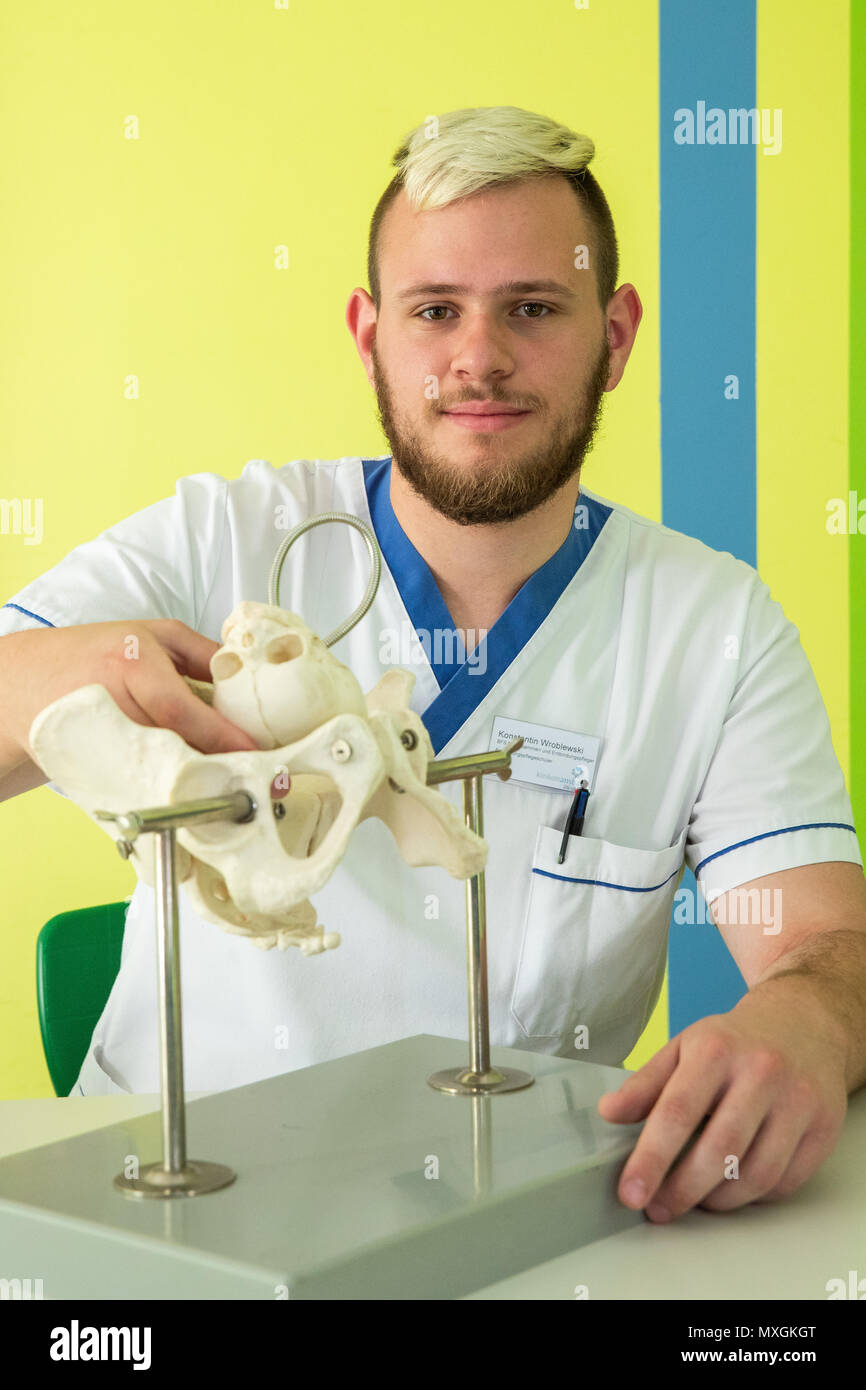 29 May 2018, Germany, Ansbach: Konstantin Wroblewski, male midwife in training at the Berufsfachschule für Hebammen und Entbindungspfleger am Klinikum Ansbach (lit. vocational school for midwifes and male midwifes at the Ansbach Clinic), sits next to a bone model of a female pelvis, in order to learn how the head of the baby has to be positioned during childbirth. Photo: Daniel Karmann/dpa Stock Photo