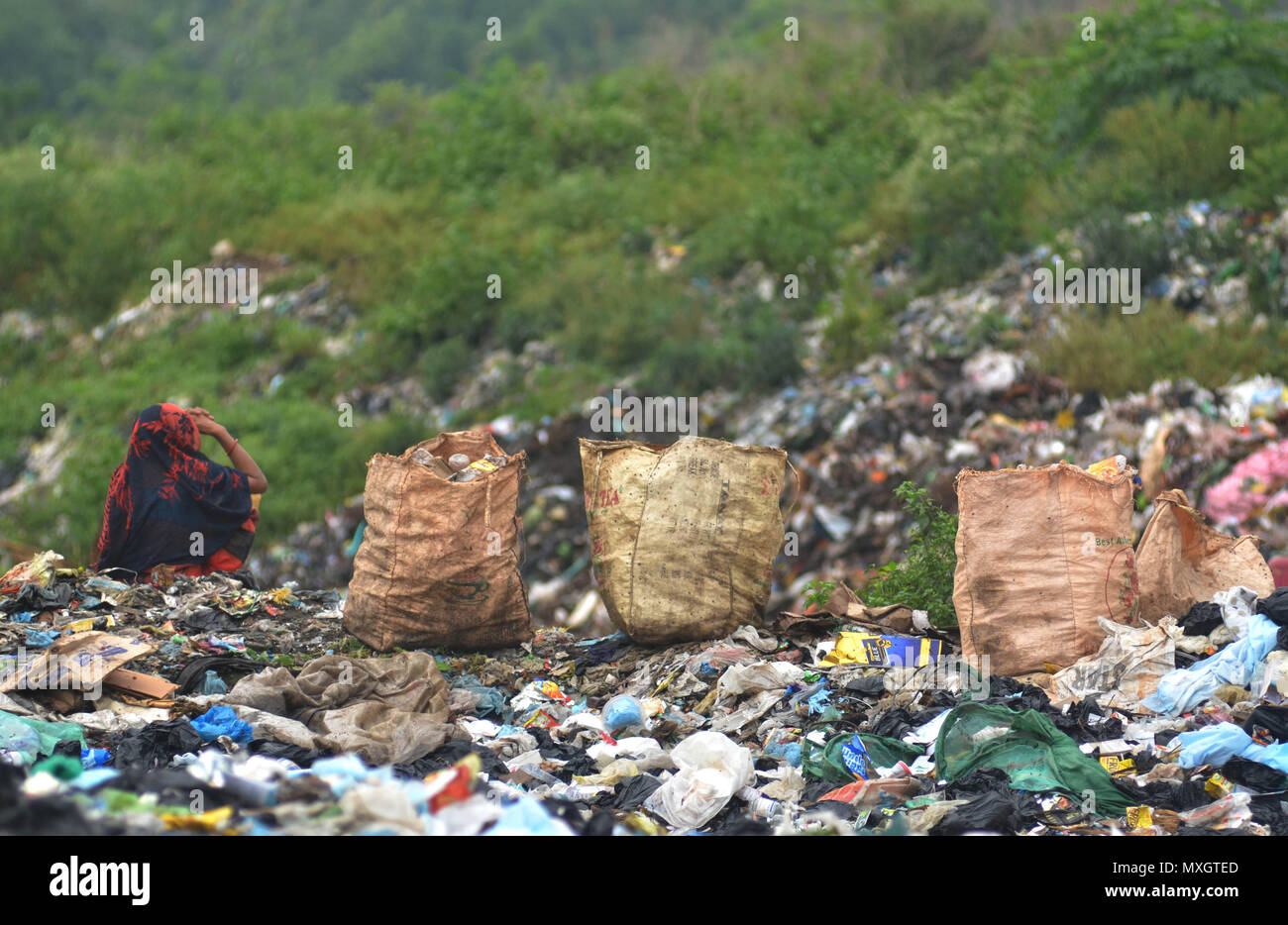 Dimapur, India - 4th June 2018: An Indian woman ragpicker sit beside bag of recycle item collected for re-use from a dumping site on the eve of World Environment Day in Dimapur, India north eastern state of Nagaland. World Environment Day is mark annually on June5 with this year theme as ‘Beat Plastic Pollution’. Credit: Caisii Mao/Alamy Live News Stock Photo