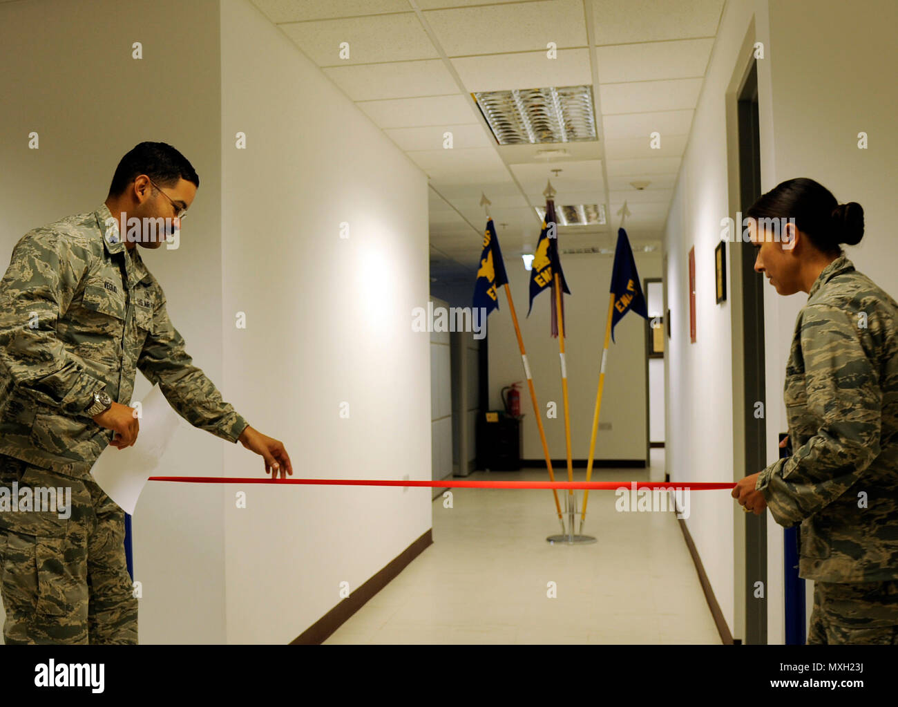 U.S. Air Force Lt. Col. Ramon Veglio, the medical logistics and readiness flight commander, left, and Lt. Col. Stella Garcia , the 379th Expeditionary Medical Support Squadron commander, both with the 379th Expeditionary Medical Group, hang the ribbon for a ribbon cutting ceremony to open the new medical administration building at Al Udeid Air Base, Qatar, Nov. 2, 2016. The expansion to the 379th EMDG will allow for apheresis, mental health, biomedical equipment repair and bioenvironmental engineering to be housed in one facility. (U.S. Air Force photo by Senior Airman Cynthia A.Innocenti) Stock Photo