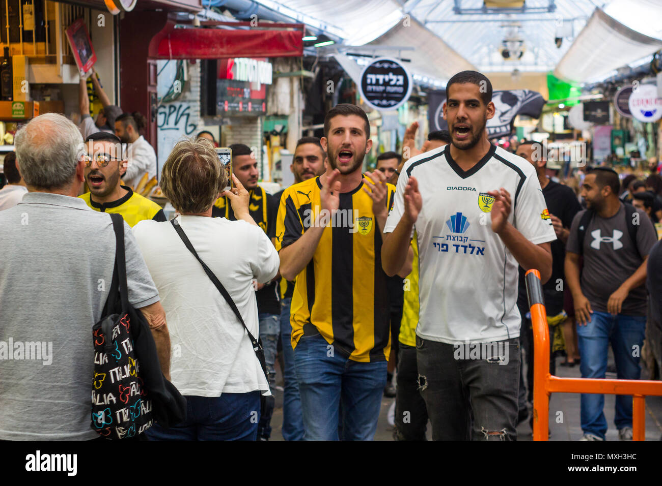 Football supporters in Beitar Jerusalem strip march down the mall of the Mahane Yehuda covered market in Jerusalem Israel. Stock Photo
