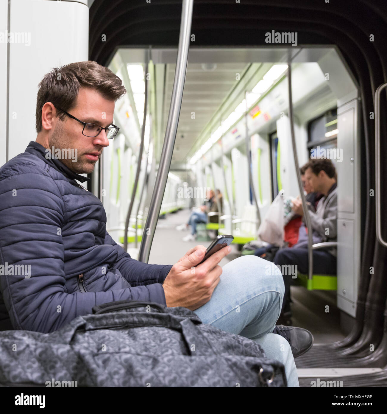 Male commuter reading from mobile phone screen in metro Stock Photo - Alamy