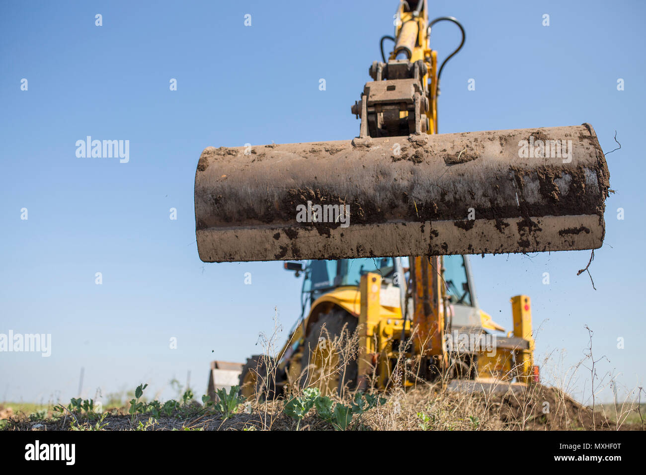 Backhoe tractor working with back long shovel. The machine is prepare the ground Stock Photo
