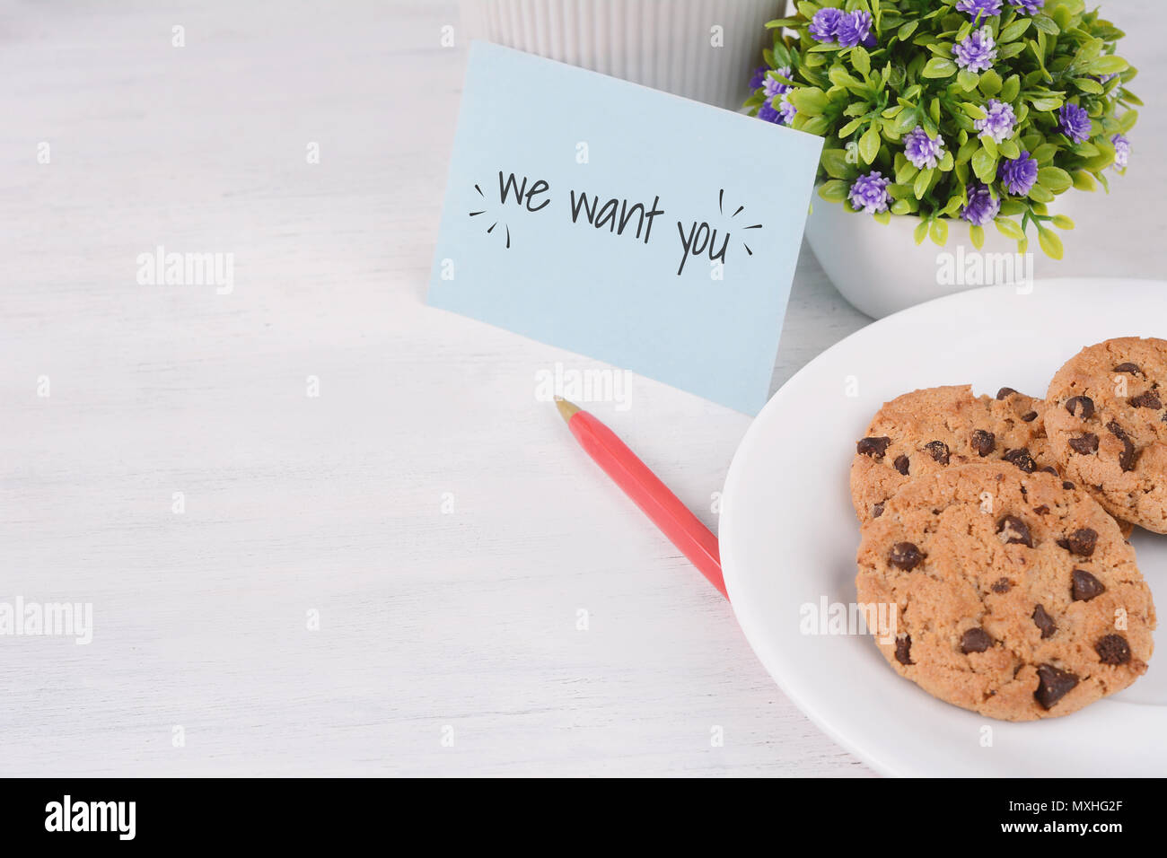 Paper note written with word 'we want you' and cookies on white wooden background. Hiring concept Stock Photo