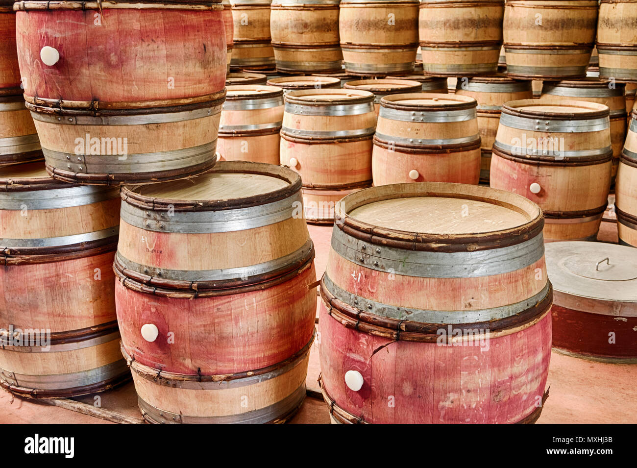 Empty barrels of wine are stacked up in a winery cellar waiting to be