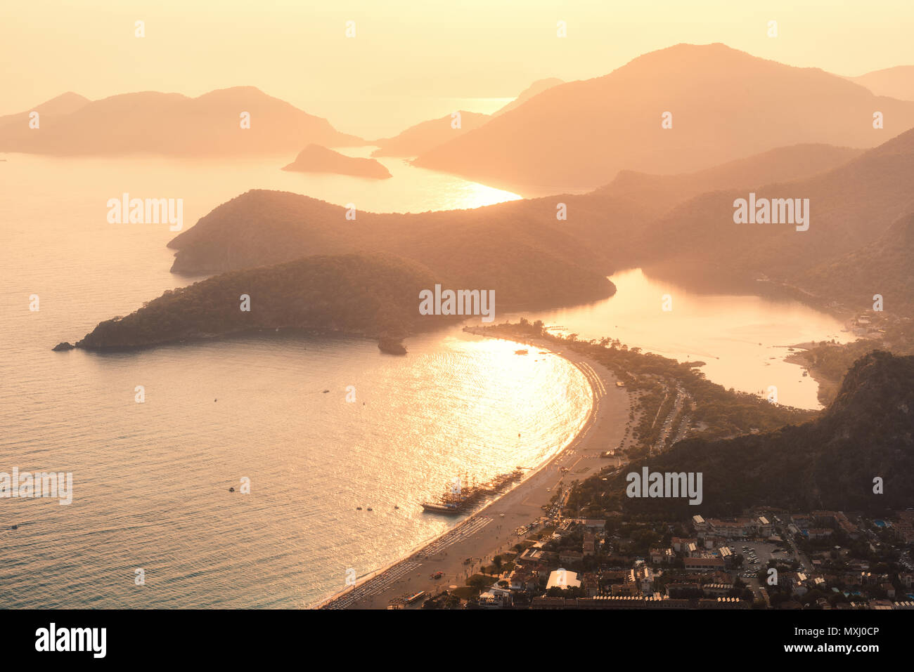 Beautiful seascape at sunset. Landscape with sea, mountains, islands, city, gold sunlight and orange sky in summer. Amazing view from the mountain pea Stock Photo