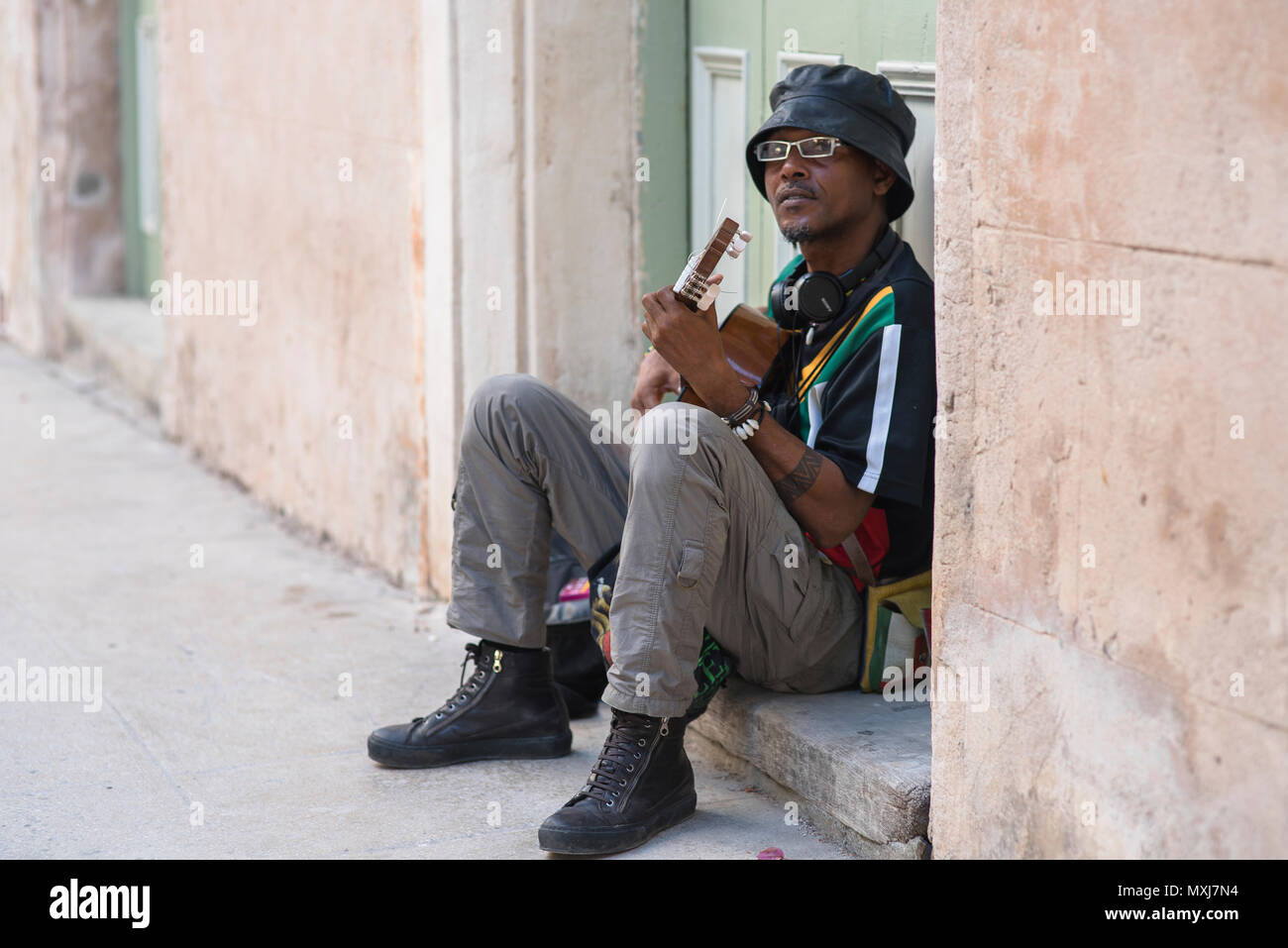 A friendly man playing guitar on a stoop in Havana, Cuba. Stock Photo