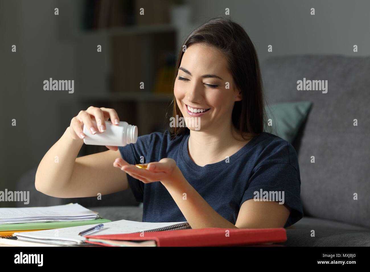 Student studying late hours taking virtamin supplement pills at home Stock Photo
