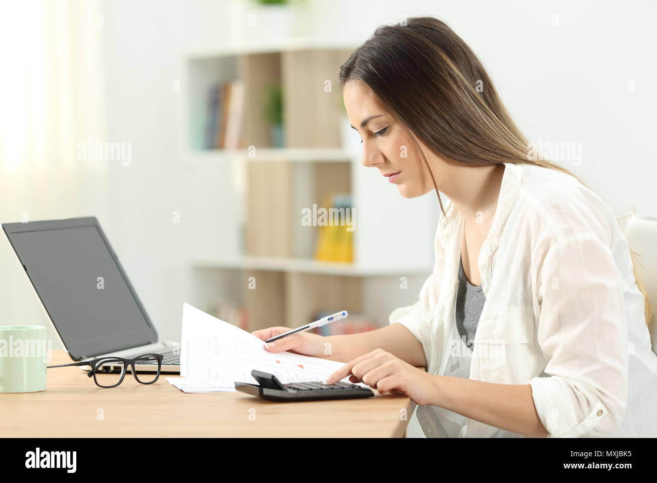 Side view portrait of a serious woman doing domestic accounting at home Stock Photo