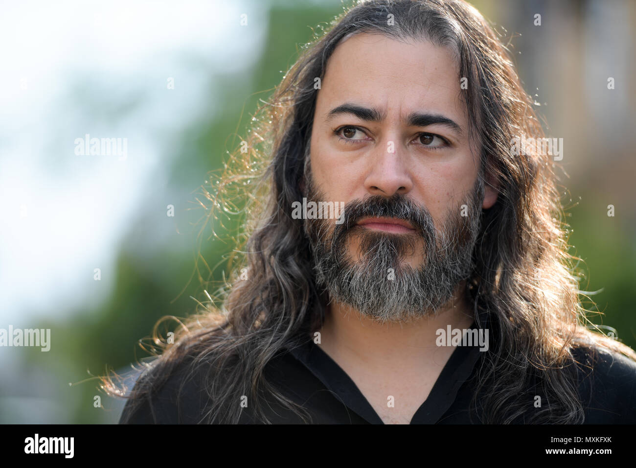 Mature handsome bearded multi-ethnic businessman with long hair in the streets outdoors Stock Photo