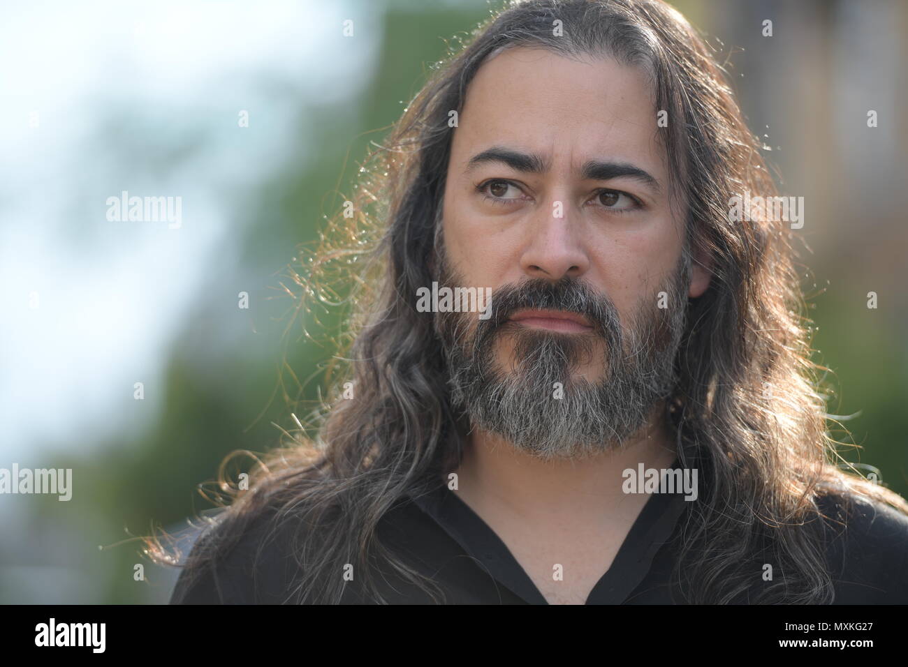 Mature handsome bearded multi-ethnic businessman with long hair in the streets outdoors Stock Photo