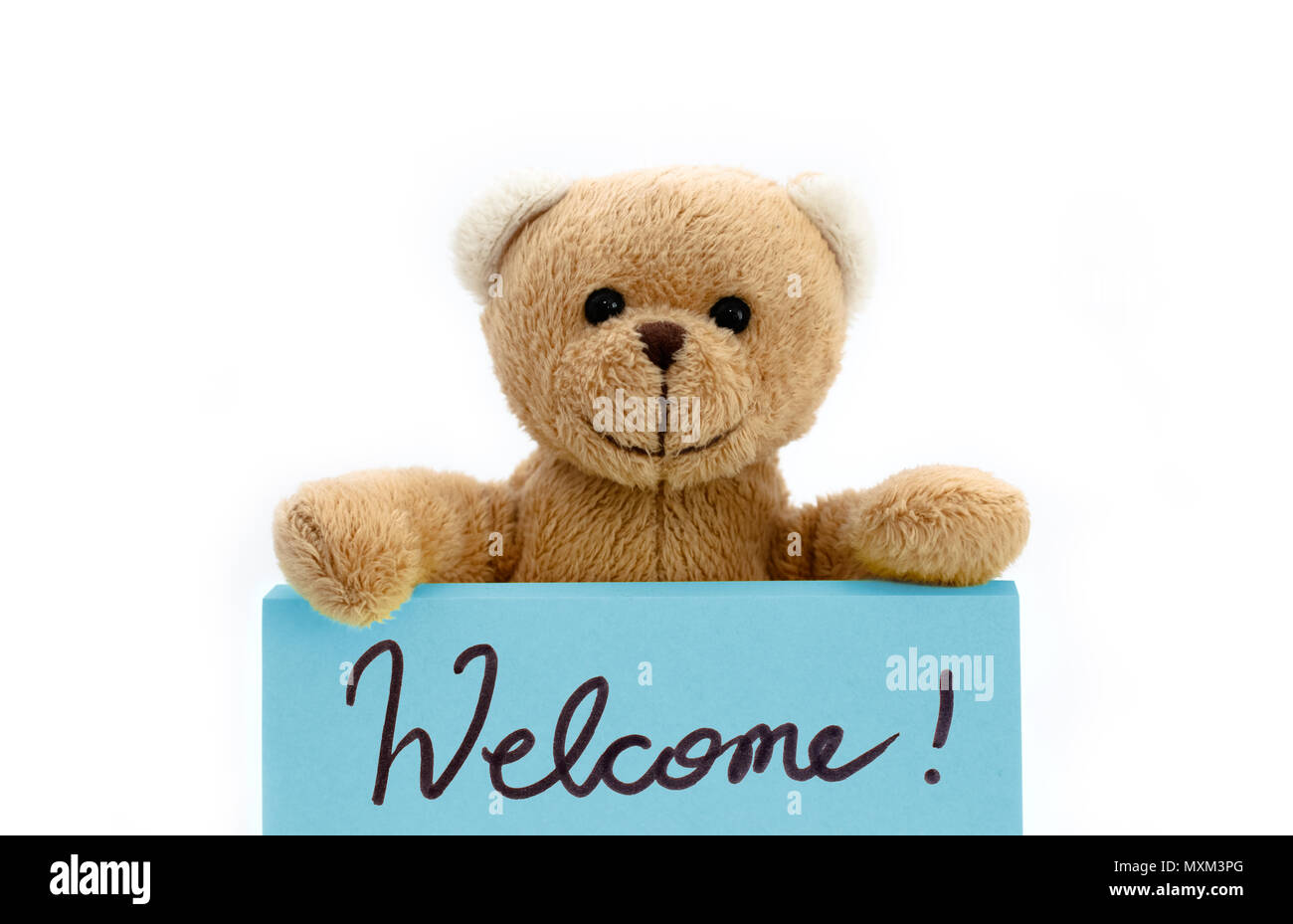 Brown teddy bear holding with the two hands a note in blue color with the handwritten message “Welcome!” as welcome sign concept. Photo isolated in a  Stock Photo