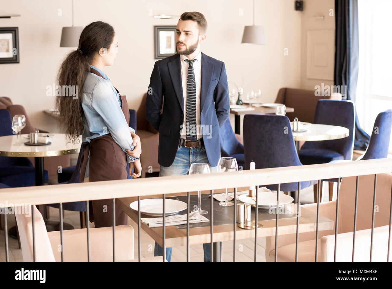 Frowning restaurateur talking to waitress Stock Photo