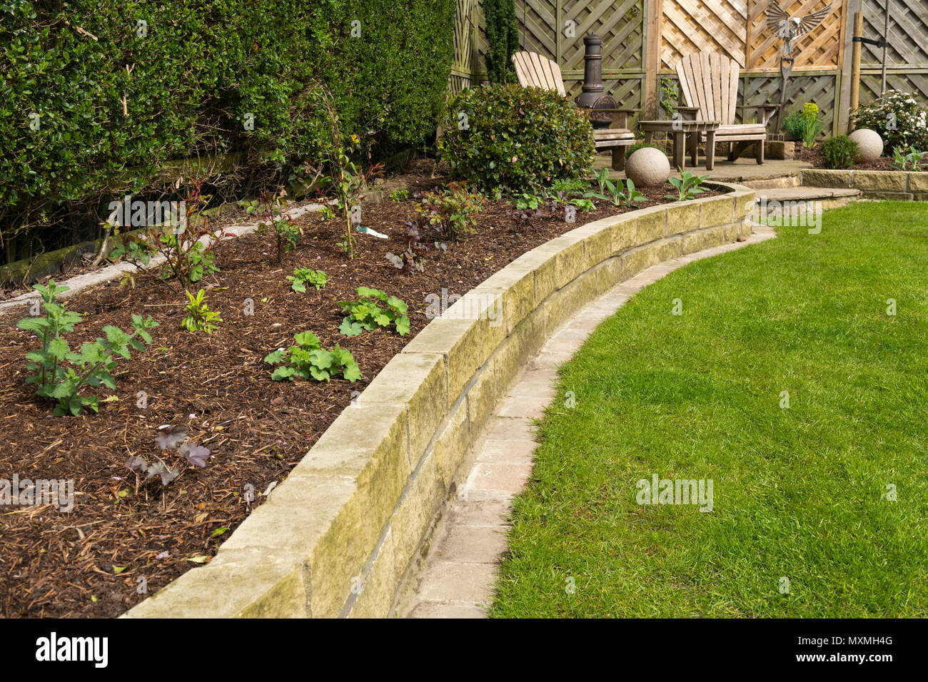 Corner of beautiful, landscaped, private garden with contemporary design, border plants, patio