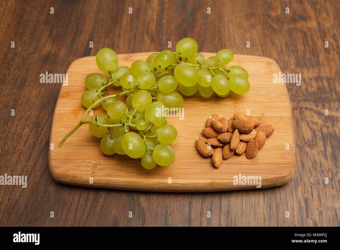 white, fresh grapes with some nuts on woden board Stock Photo