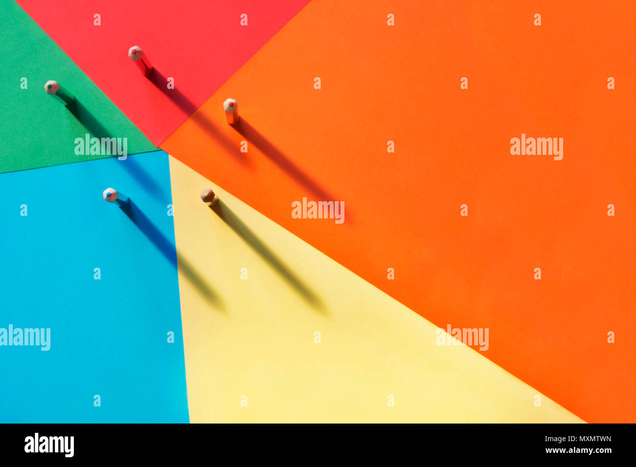 Five different colored pencils on a multicolored background, light shadow on the background .A horizontal and graphic composition,rainbow effect Stock Photo