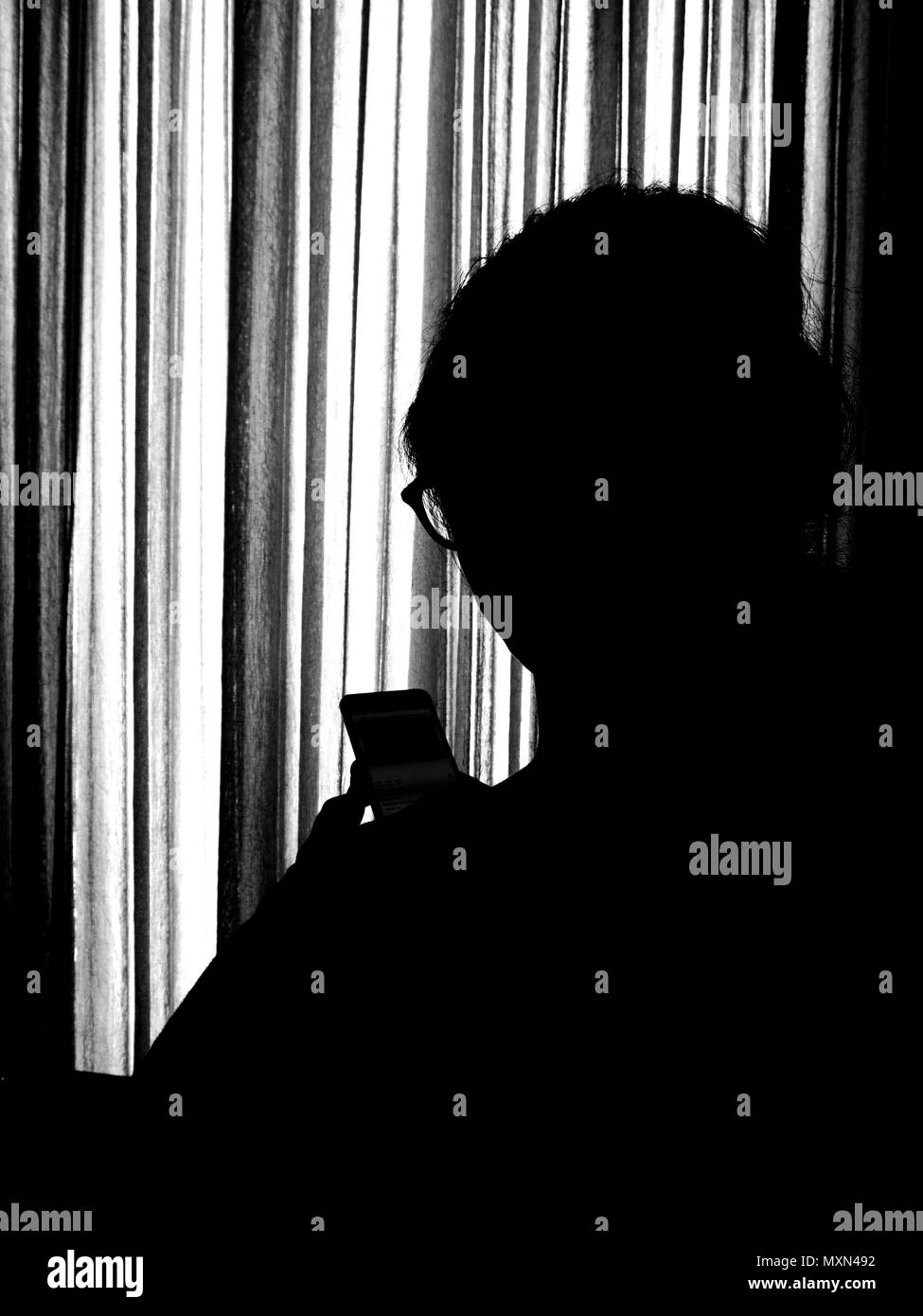 Silhouette of a teenaged girl using her mobile phone. Stock Photo