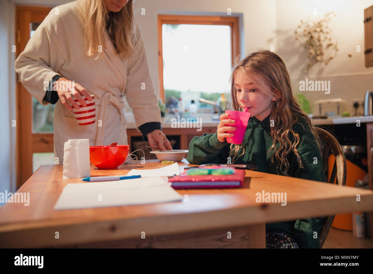 Mother cleaning up after her daughter has finished breakfast Stock Photo