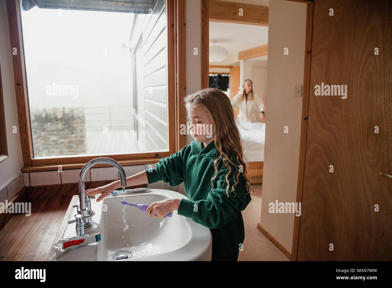 Little girl dressed in a school uniform brushing her teeth before going to school. Stock Photo