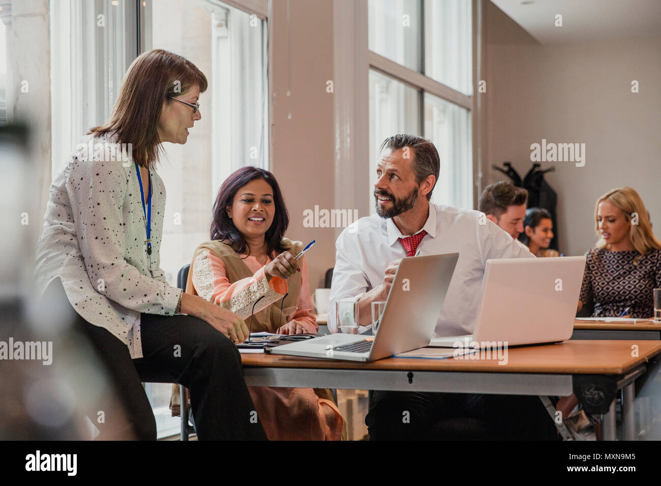 Co-workers talking though information on a laptop in a board room. Having a meeting in the conference. Stock Photo