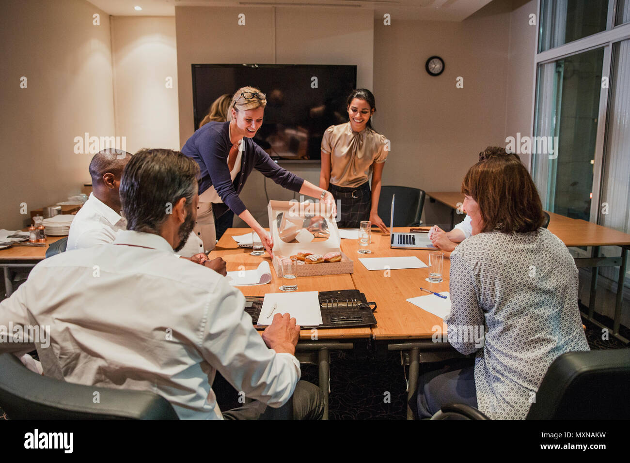 Rear View Of A Group Of Business People Working Late At The Office One Of The Business People Bought Some Doughnuts As A Treat Stock Photo Alamy