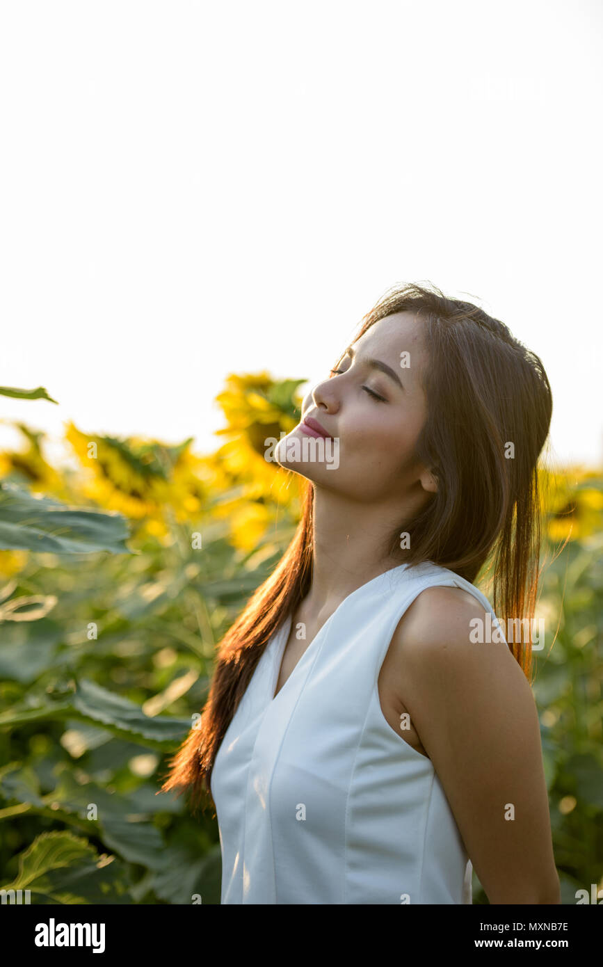 Young beautiful Asian woman with eyes closed in the field of blo Stock ...