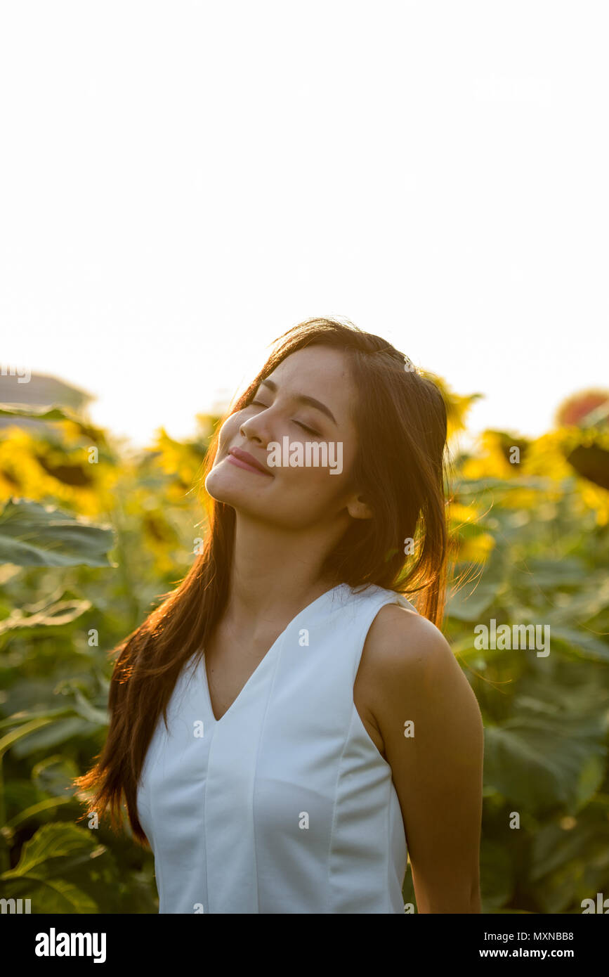 Young beautiful Asian woman with eyes closed in the field of blo Stock ...