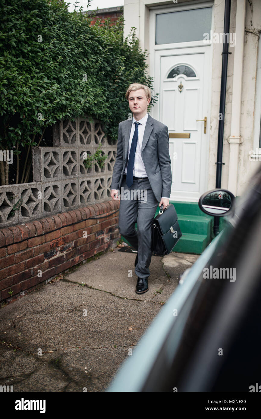 Young businessman walking out the house to go tot the car to commute to work. Stock Photo