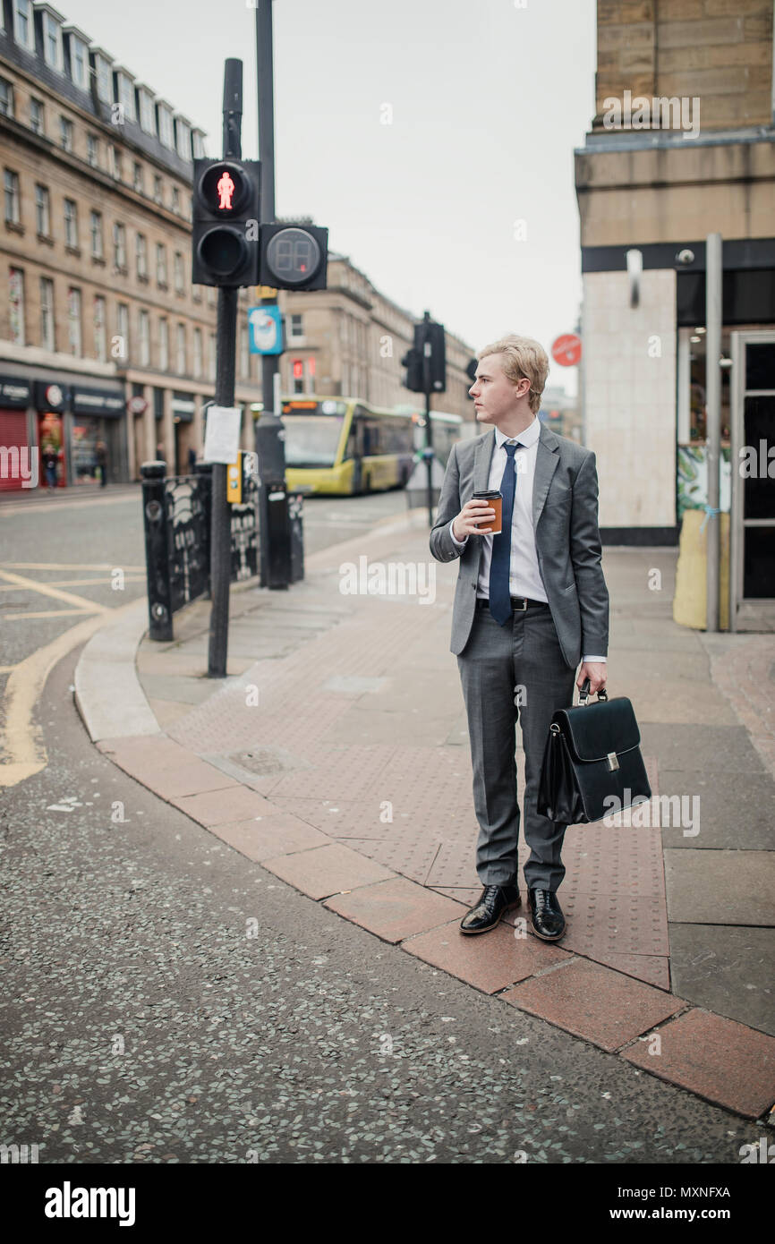 Front view of a young businessman waiting at the traffic lights to cross the road. Stock Photo