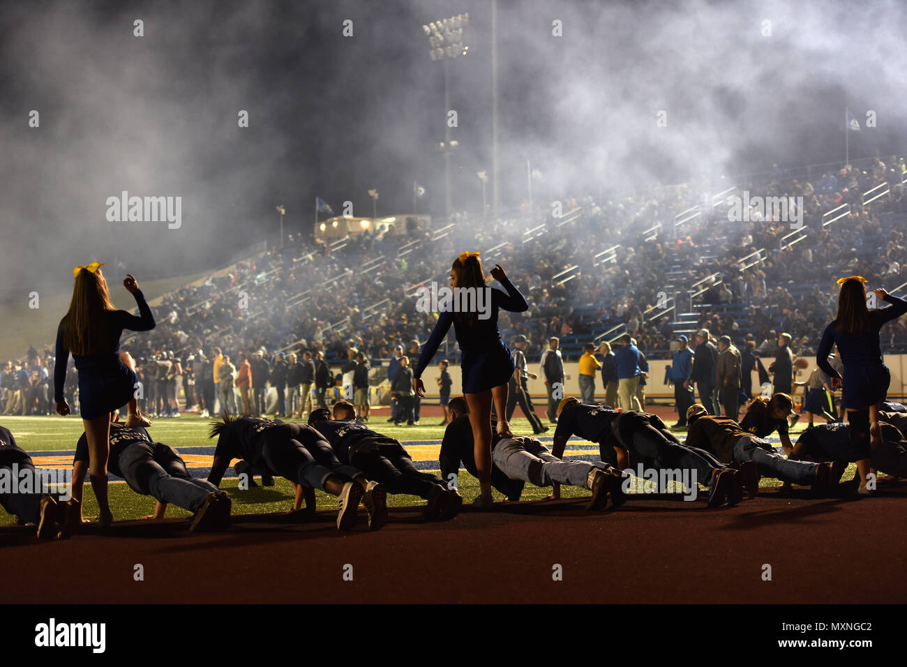 Angelo State University cheerleaders mock step on Junior ROTC units at the ASU Military Appreciation football game at San Angelo Stadium, Texas, Nov. 12, 2016. The Junior ROTC cadets performed pushups every time ASU scored a touchdown. (U.S. Air Force photo by Airman 1st Class Caelynn Ferguson/Released) Stock Photo