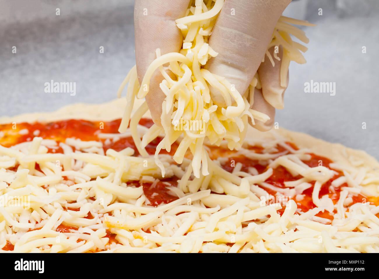 Homemade pizza human hand with gloves spreading mozzarella cheese on