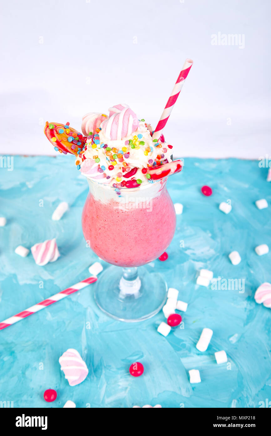 https://c8.alamy.com/comp/MXP218/pink-extreme-milkshake-with-berry-rasberry-strawberry-candy-marshmallow-lollipops-on-blue-background-crazy-freakshake-copy-space-food-trend-ov-MXP218.jpg