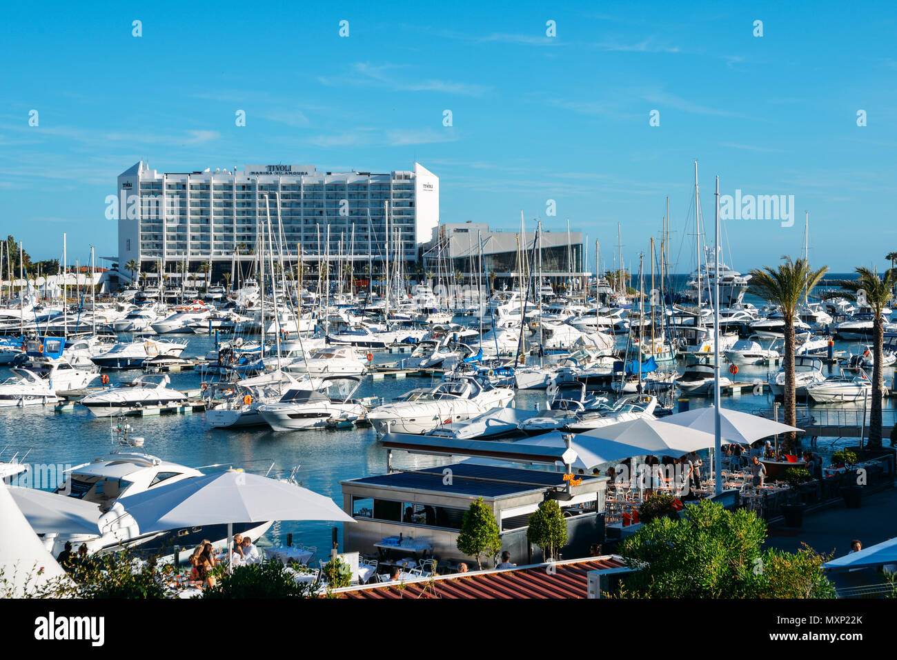 Promenade full of families next to marina at the fashionable resort town of VilaMoura in the southern Portuguese region of Algarve. Luxury Tivoli Hotel visible Stock Photo
