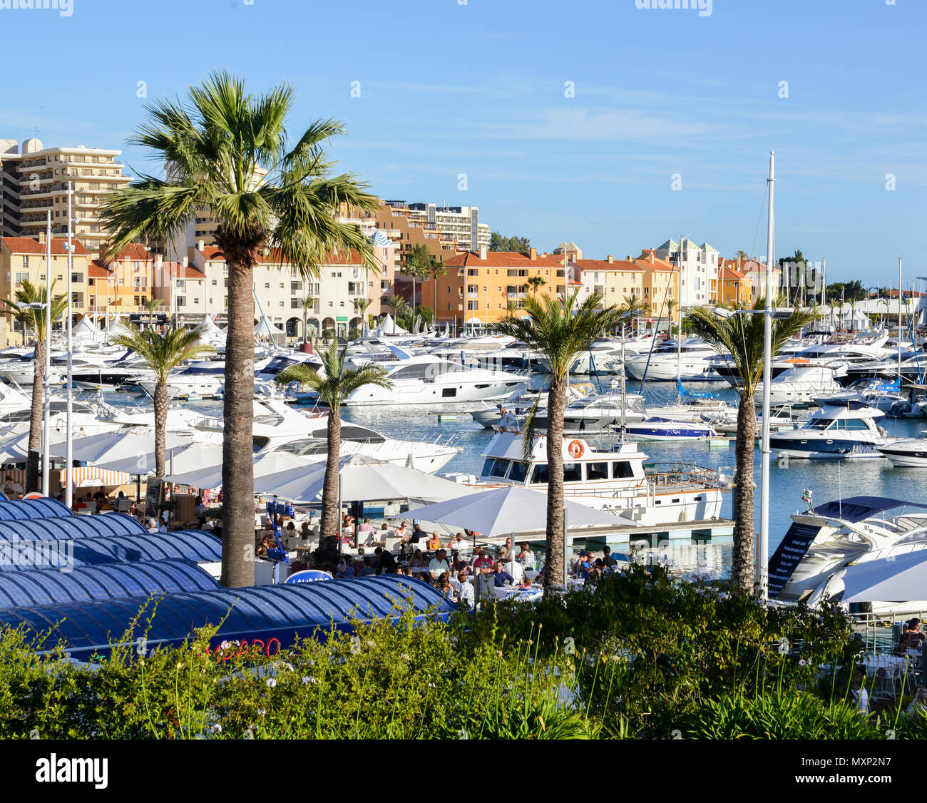 Promenade full of families next to marina at the fashionable resort town of VilaMoura in the southern Portuguese region of Algarve. Luxury Tivoli Hotel visible Stock Photo