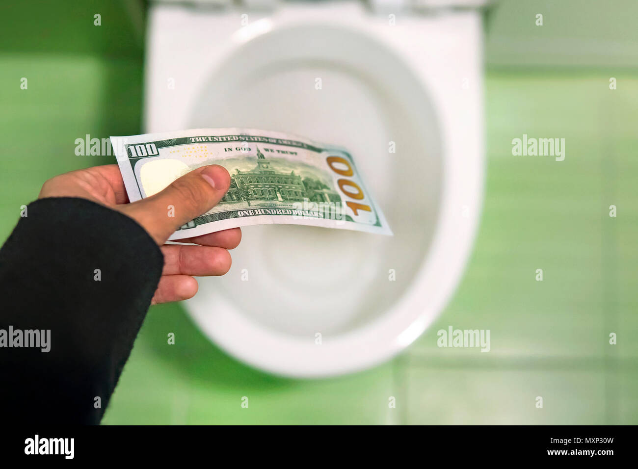 Flush money down the toilet, throws dollar bills in the toilet, loss concept, close up, selective focus. concept of senseless waste of money, loss, us Stock Photo