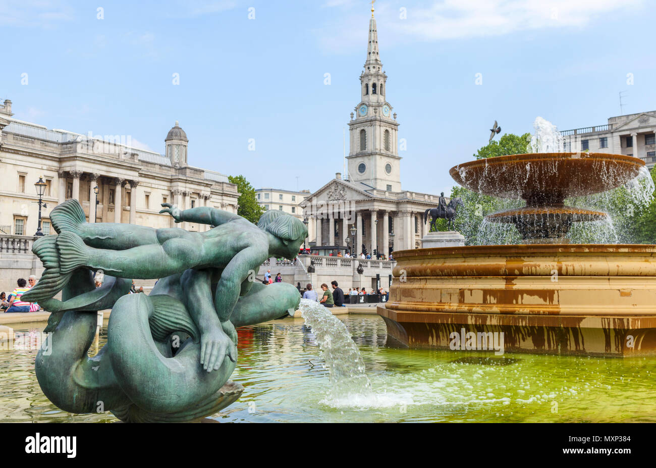 Mermaid statue in the fountains at Trafalgar Square, Westminster, central London WC2 St Martin in the Fields church and the National Gallery behind Stock Photo