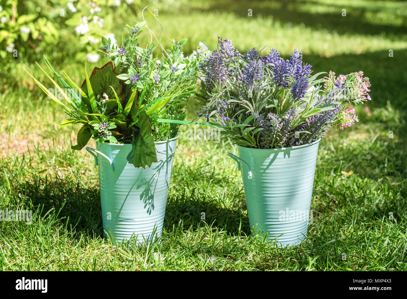 Various fresh flowers arrangement in metalic buckets in the garden