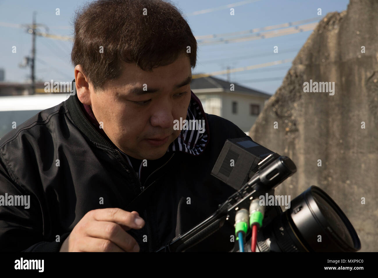 Yamaguchi Yuki, a videographer for Hakuhodo Inc., checks the settings on  his camera at Marine Corps Air Station Iwakuni, Japan, Nov. 29, 2016. Yuki  took video of the hangar to show the