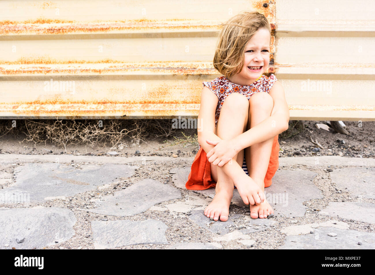 female child sitting on crazy paving alone Stock Photo