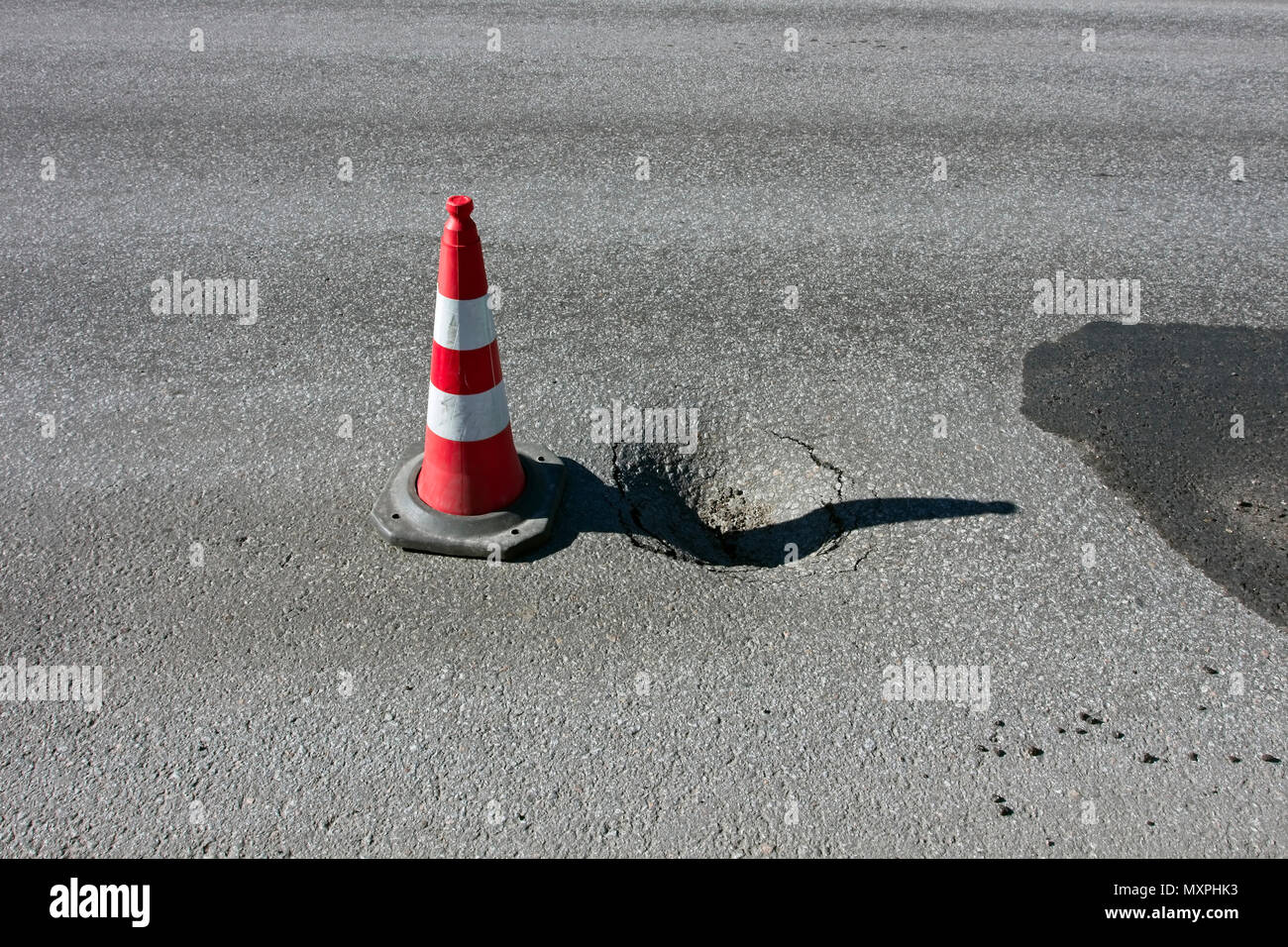 pothole damage with traffic cone on road Stock Photo