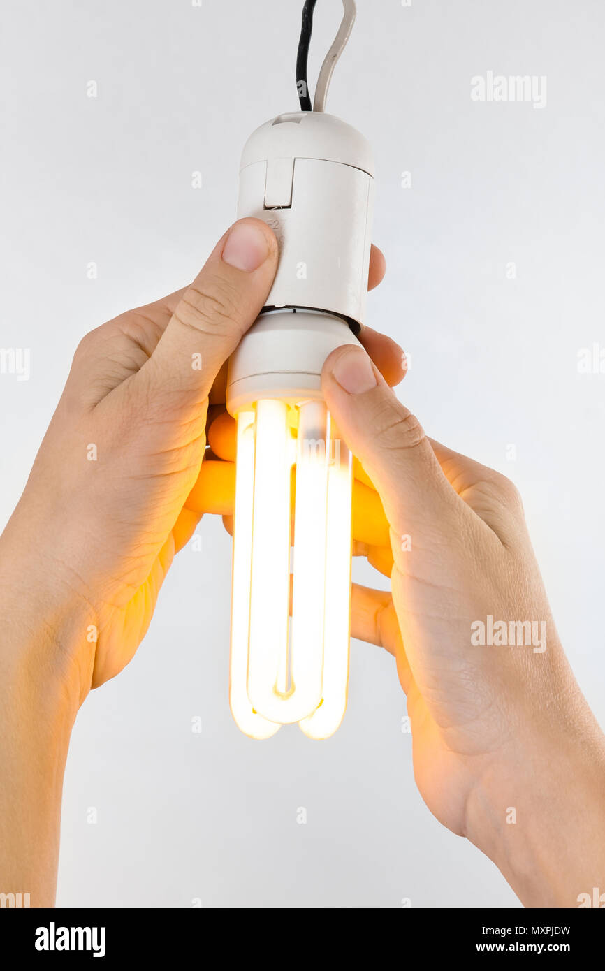 hands replacing energy saving light bulb, closeup Stock Photo