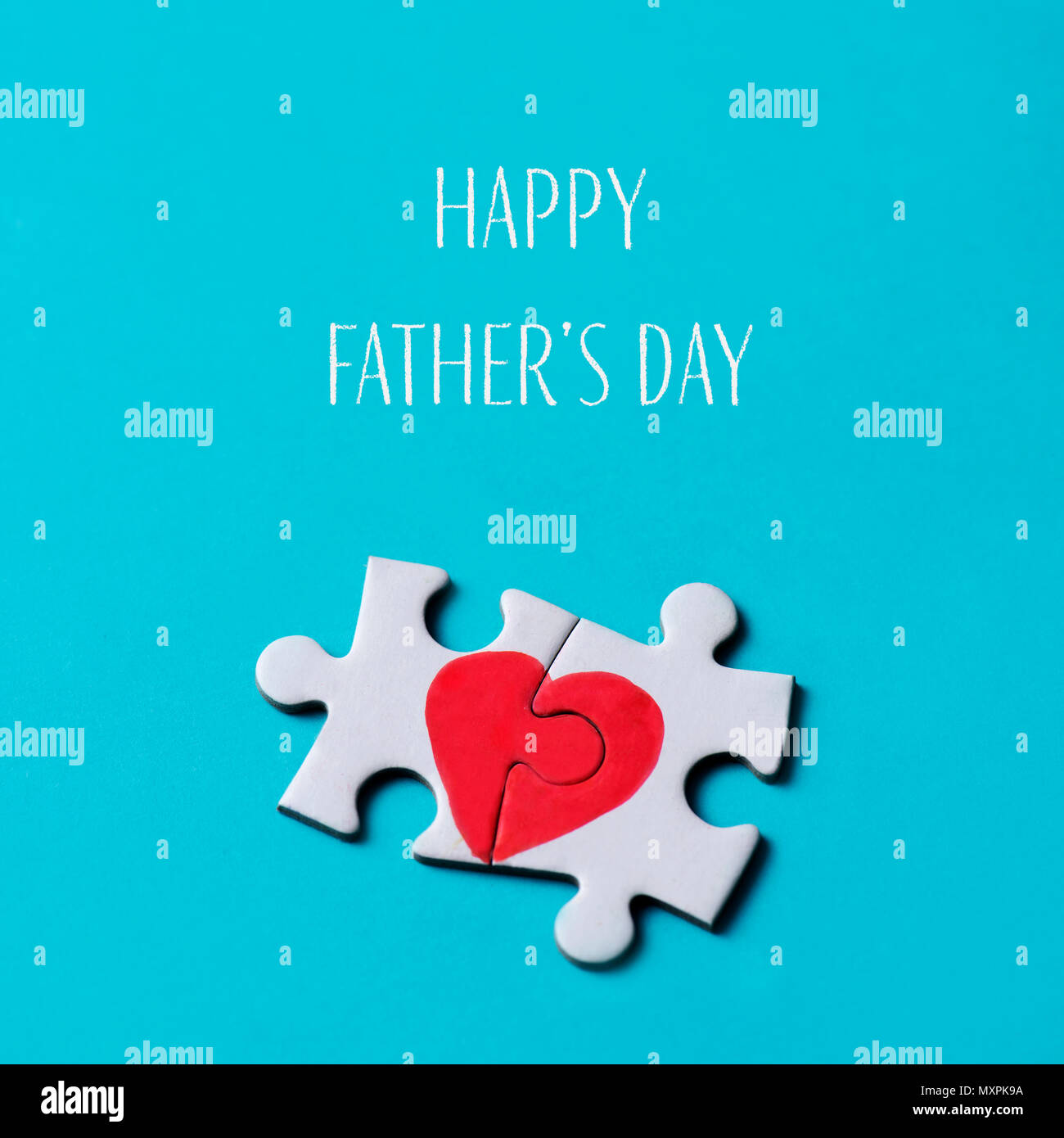 two pieces of a puzzle forming a heart and the text happy fathers day on a blue background Stock Photo