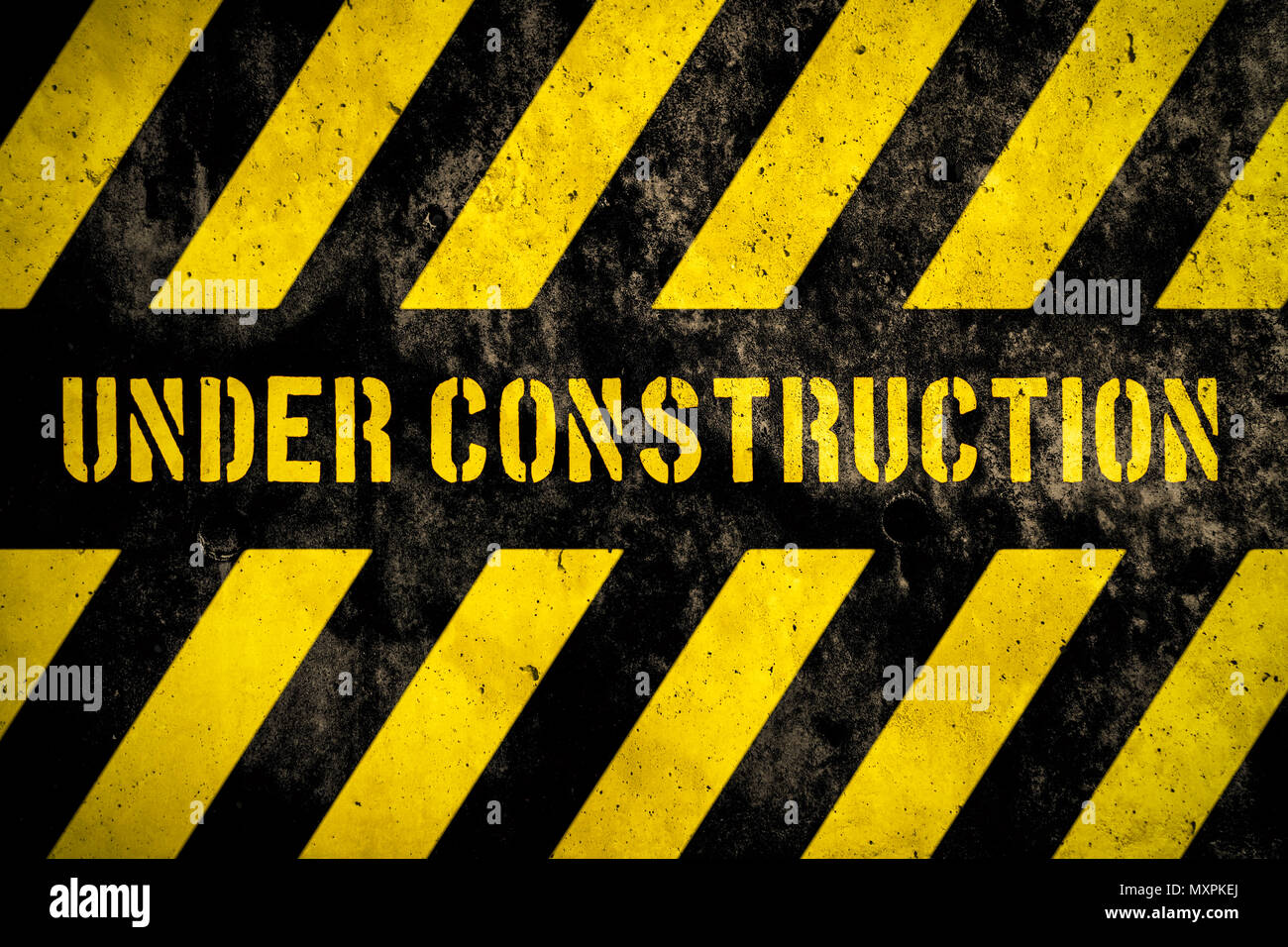Under construction warning sign with yellow and dark stripes painted