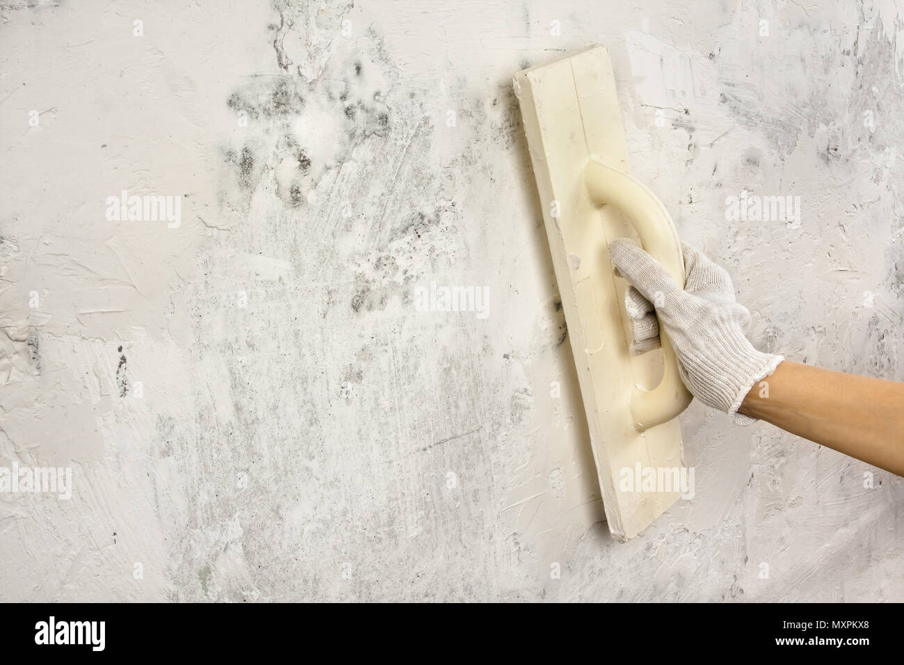 hand plastering and smoothing concrete wall with trowel during repair Stock Photo