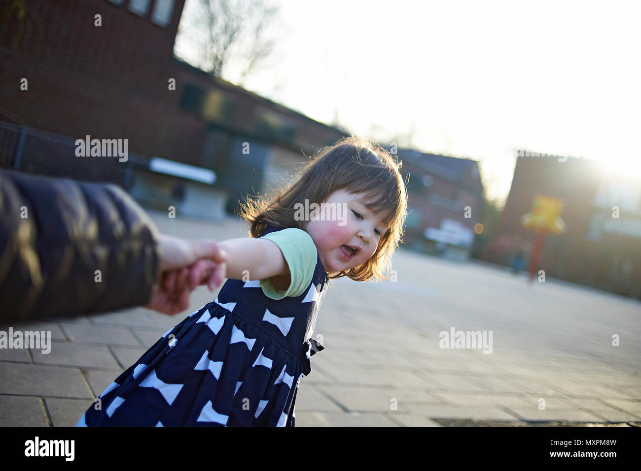 Excited happy cute young Japanese baby girl pulling her mother's arm to