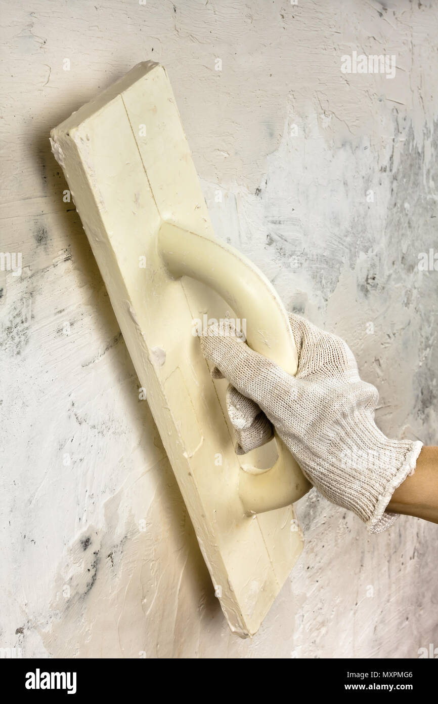hand with trowel plastering concrete wall during repair Stock Photo